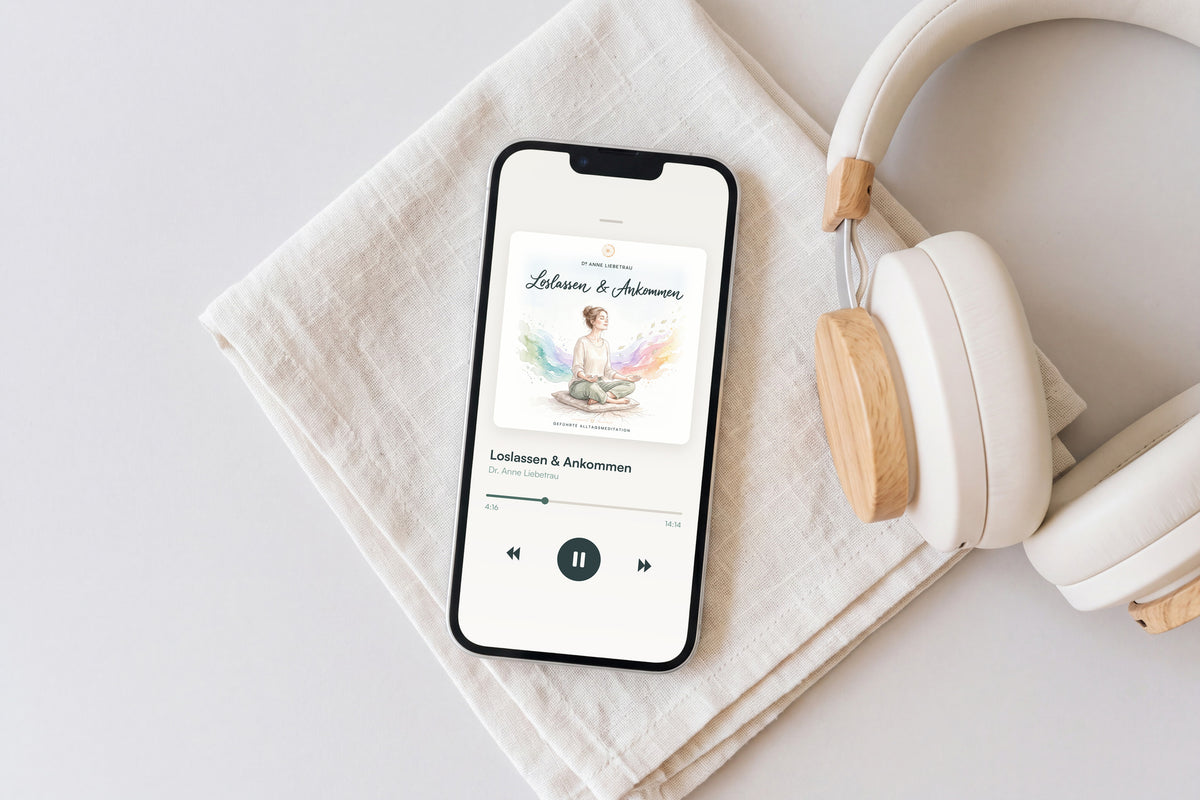 Smartphone mit dem Cover der Meditation „Loslassen & Ankommen“ auf Leinen, daneben Kopfhörer