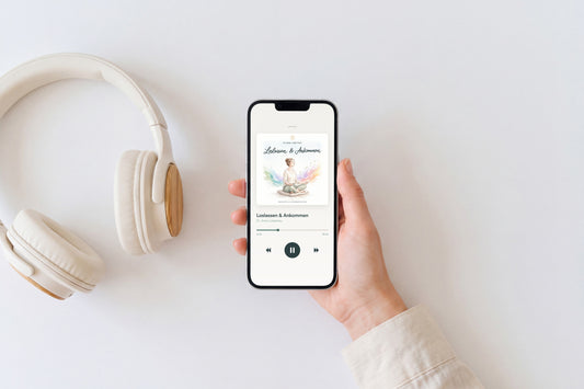 Hand hält ein Smartphone mit dem Player der geführten Alltagsmeditation „Loslassen & Ankommen“ von Dr. Anne Liebetrau, daneben Kopfhörer